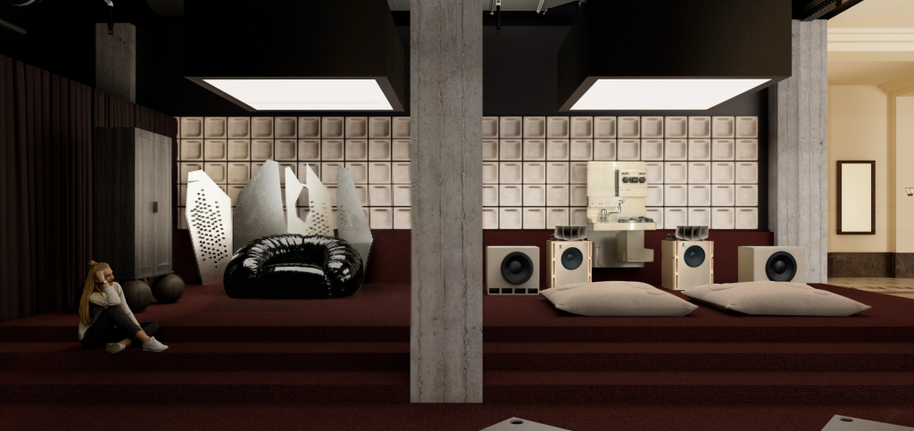 A modern room with maroon carpeted steps, high ceilings, a black chair, abstract white sculptures, audio equipment, two large speakers, floor cushions, and a woman with blonde hair sitting by a column.