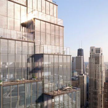 Modern glass skyscraper with multiple terraces and balconies, overlooking surrounding city buildings and a body of water under a clear sky at sunrise or sunset.