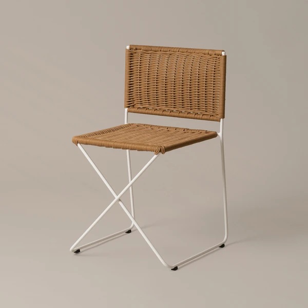 A folding chair with a woven rattan seat and backrest, featuring a white metal X-shaped frame, set against a plain light gray background.