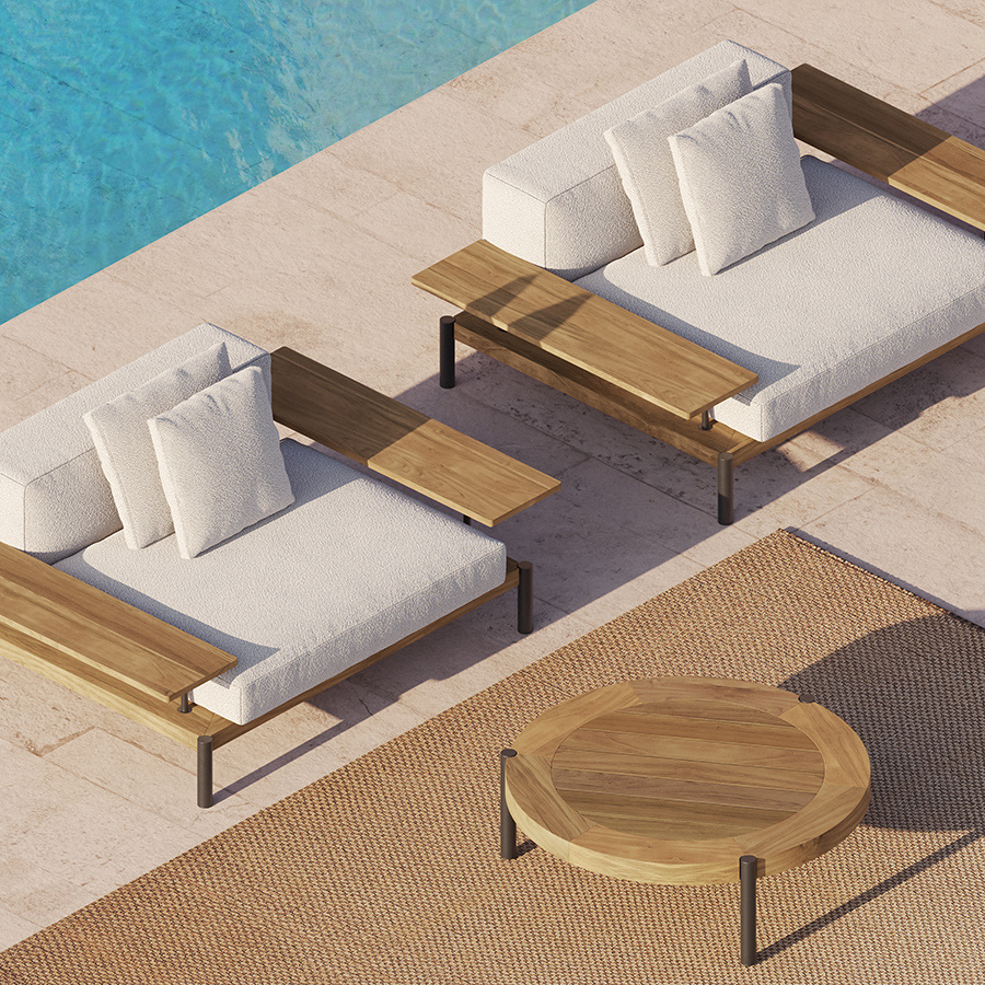 Two modern outdoor lounge chairs with white cushions and wooden armrests sit by a blue pool, next to a round wooden table on a woven rug over beige stone tiles.